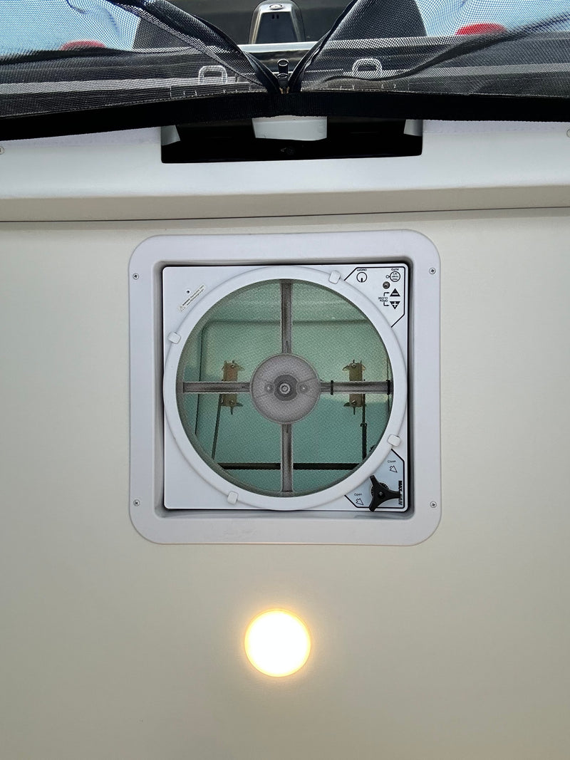 RV rental overhead view: MaxxAir ceiling vent fan with screen, an overhead light, and a black mesh privacy screen. — photo 4