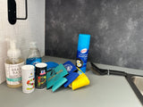 RV rental kitchen counter: dish soap, salt, spices, koozies, cooking spray, and grill brush next to the sink.