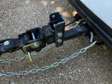 Close-up of an RV rental's weight distribution tow hitch and safety chains, securely attached for trailer towing.