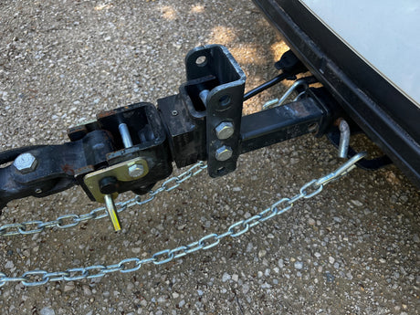 Close-up of an RV rental's weight distribution tow hitch and safety chains, securely attached for trailer towing.