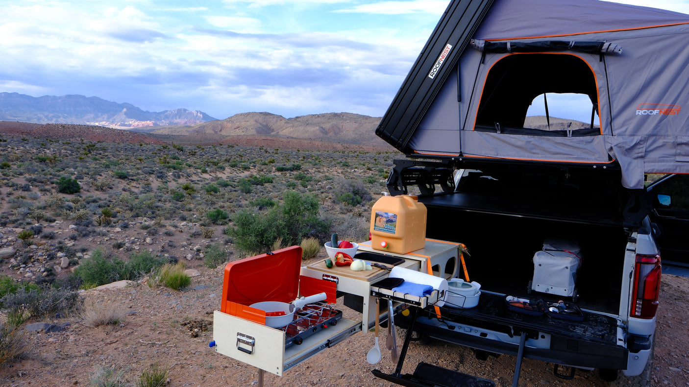Overlanding setup: RV rental-ready truck with a Roofnest rooftop tent & full outdoor kitchen in a desert landscape.