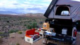 Overlanding setup: RV rental-ready truck with a Roofnest rooftop tent & full outdoor kitchen in a desert landscape.