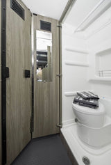 This compact RV rental bathroom includes a toilet, shower, and space-saving folding door.