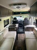 Inside an RV rental: a spacious camper van interior with kitchen, living/sleeping areas, and front cab view, ideal for travel.