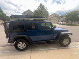 Adventure-ready blue Jeep Wrangler with a rooftop tent, ideal for your next RV rental road trip. Perfect for overland camping!