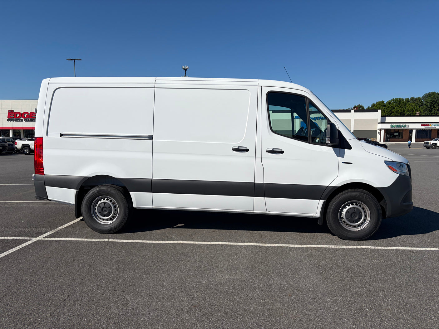 Side view of a white cargo van, a common choice for RV rental conversions, parked in a sunny lot.