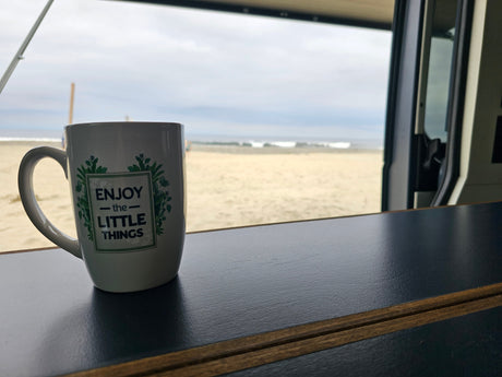 Enjoy the beach view from this RV rental! A white mug with 'Enjoy the Little Things' sits on the counter.