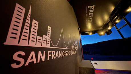 San Francisco Overland RV rental shows cityscape graphic & Freespirit Recreation tent setup at dusk, ready for adventure.