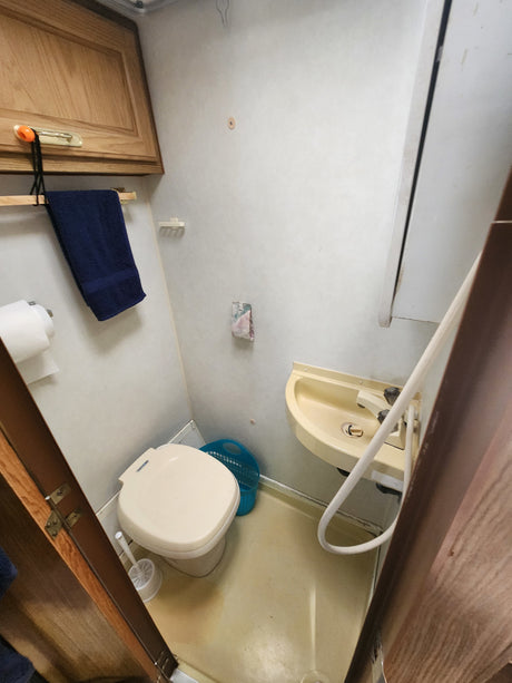 RV rental bathroom interior with toilet, sink, and shower hose. Compact and functional space for travel.