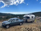 A blue truck tows an Airstream RV rental, ready for scenic camping & outdoor adventure.