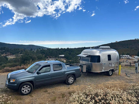 A blue truck tows an Airstream RV rental, ready for scenic camping & outdoor adventure.