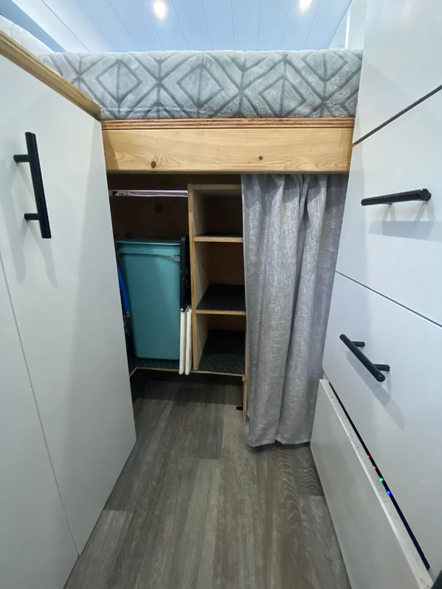 RV rental interior: a neatly designed space with cozy bed, overhead cabinets, and cubby storage for trips.