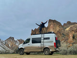 Adventure seekers atop their RV rental van, celebrating amidst striking rock formations.