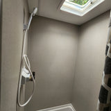 Inside an RV rental shower: a compact space with a handheld shower, neutral walls, and a skylight for natural light.