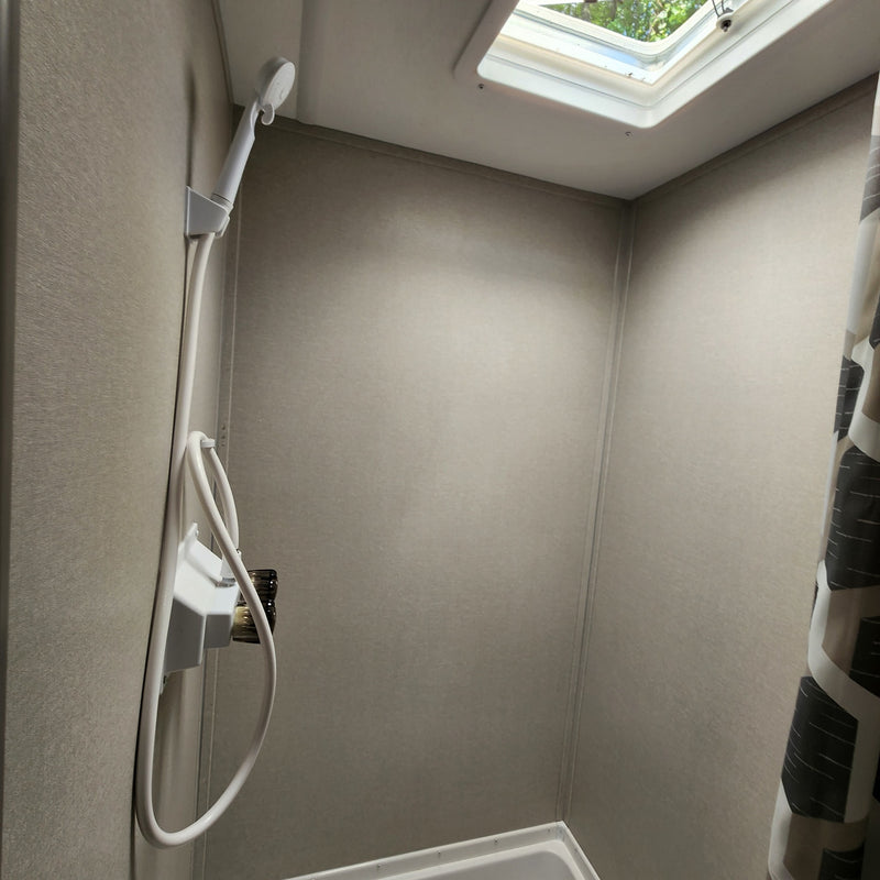Inside an RV rental shower: a compact space with a handheld shower, neutral walls, and a skylight for natural light. — photo 9