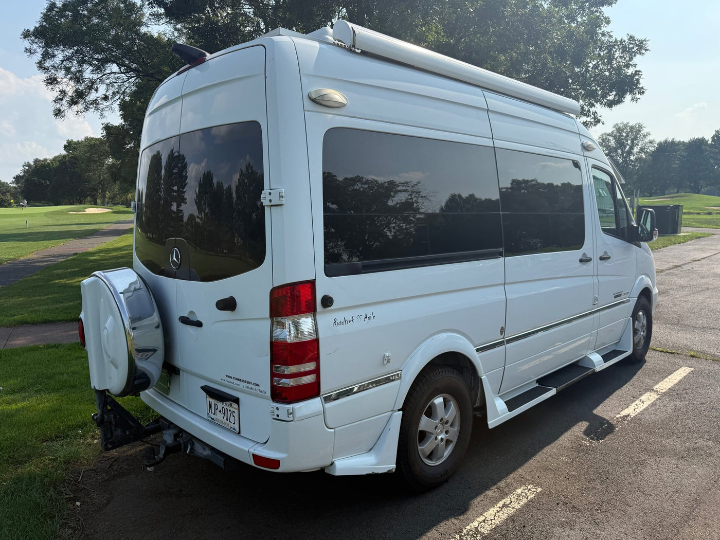  parked on asphalt next to grass under a blue sky with trees.|White Roadtrek SS Agile rv rental campervan (Mercedes-Benz Sprinter) parked outdoors — photo 5