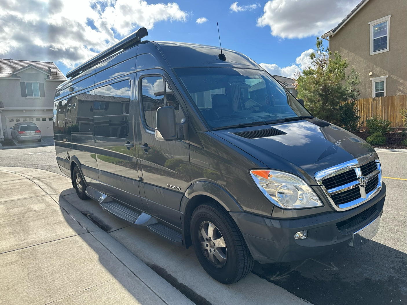 This grey Dodge Sprinter rv rental, a versatile camper van, awaits your next road trip on a sunny day.