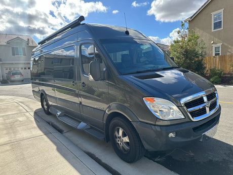 This grey Dodge Sprinter rv rental, a versatile camper van, awaits your next road trip on a sunny day.
