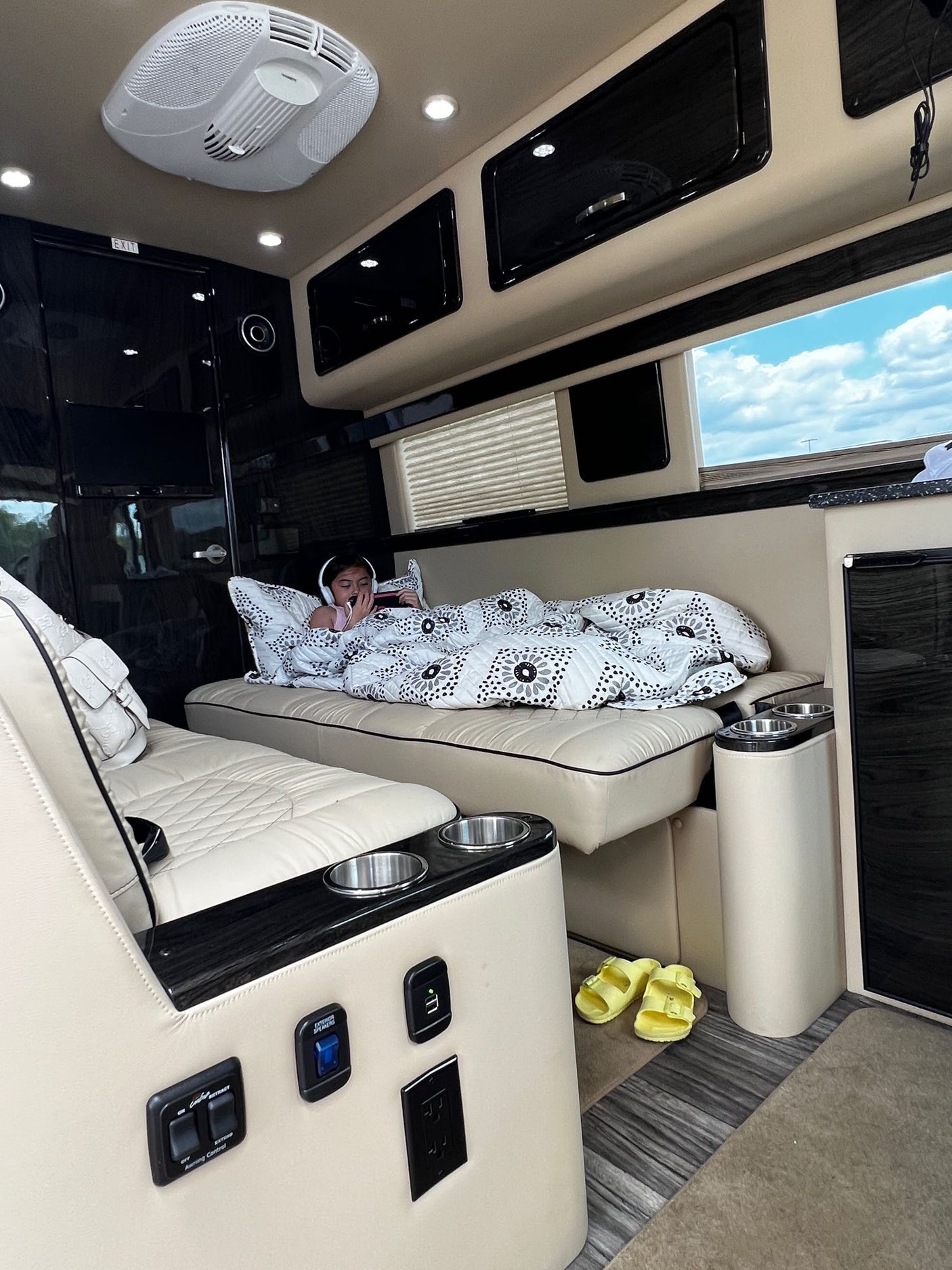 Child enjoys the plush interior of an RV rental, relaxing with a blanket & headphones. Ideal travel comfort.