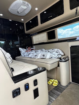 Child enjoys the plush interior of an RV rental, relaxing with a blanket & headphones. Ideal travel comfort.