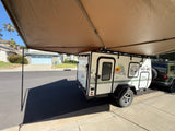 This No Boundaries NB10.6 camper, ideal for an RV rental, features an extended awning on a sunny street.