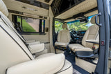Inside a spacious RV rental: luxurious cream interior with quilted seats, dark wood accents, and modern amenities for travel comfort.
