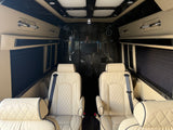 Plush RV rental interior features cream quilted leather captain's chairs, dark wood paneling, TV, and chrome accents for comfort.