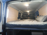 Cozy RV rental interior featuring a comfortable bed and wood paneling, ideal for road trips.