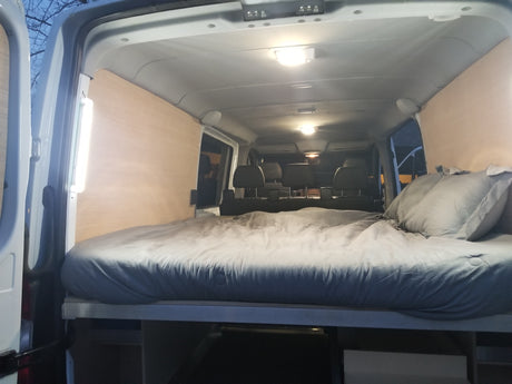 Cozy RV rental interior featuring a comfortable bed and wood paneling, ideal for road trips.