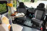 Swivel seats and a table set for breakfast with sunflowers and a book inside an RV rental camper van.