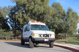 White Ford E-Series van RV rental, equipped for adventure, parked outdoors. Perfect camper van for travel.