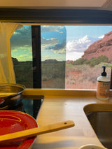 Our RV rental kitchen: sink, cooktop, and a spectacular red rock desert view from the window.