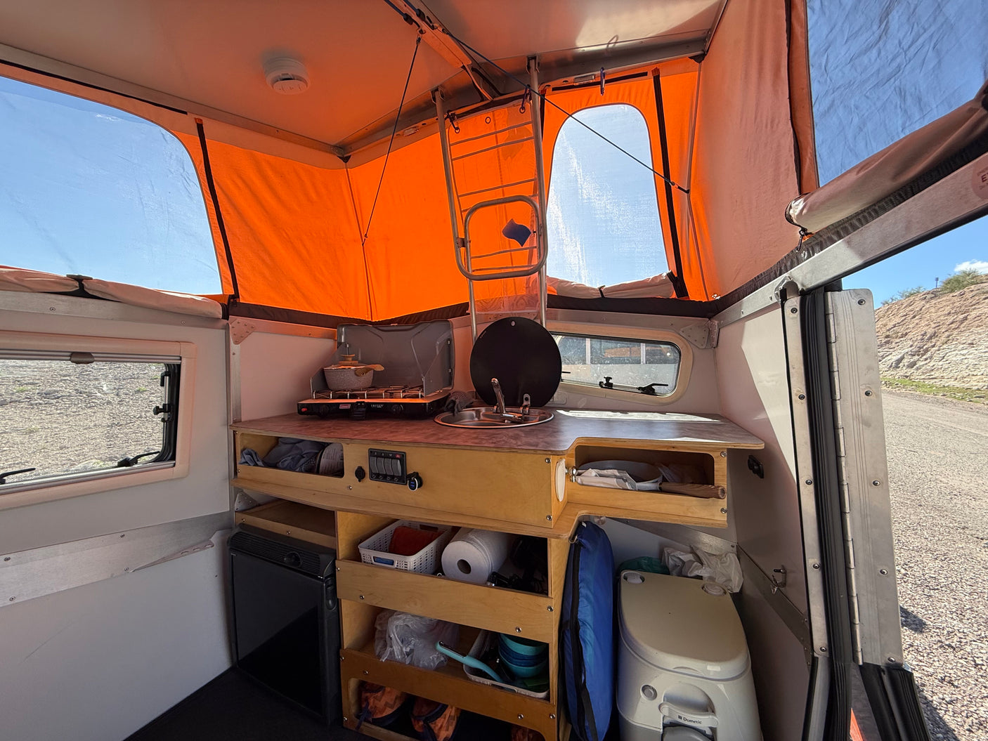 Inside this compact RV rental: an efficient kitchen, ample storage, fridge, and portable toilet for comfortable camping.