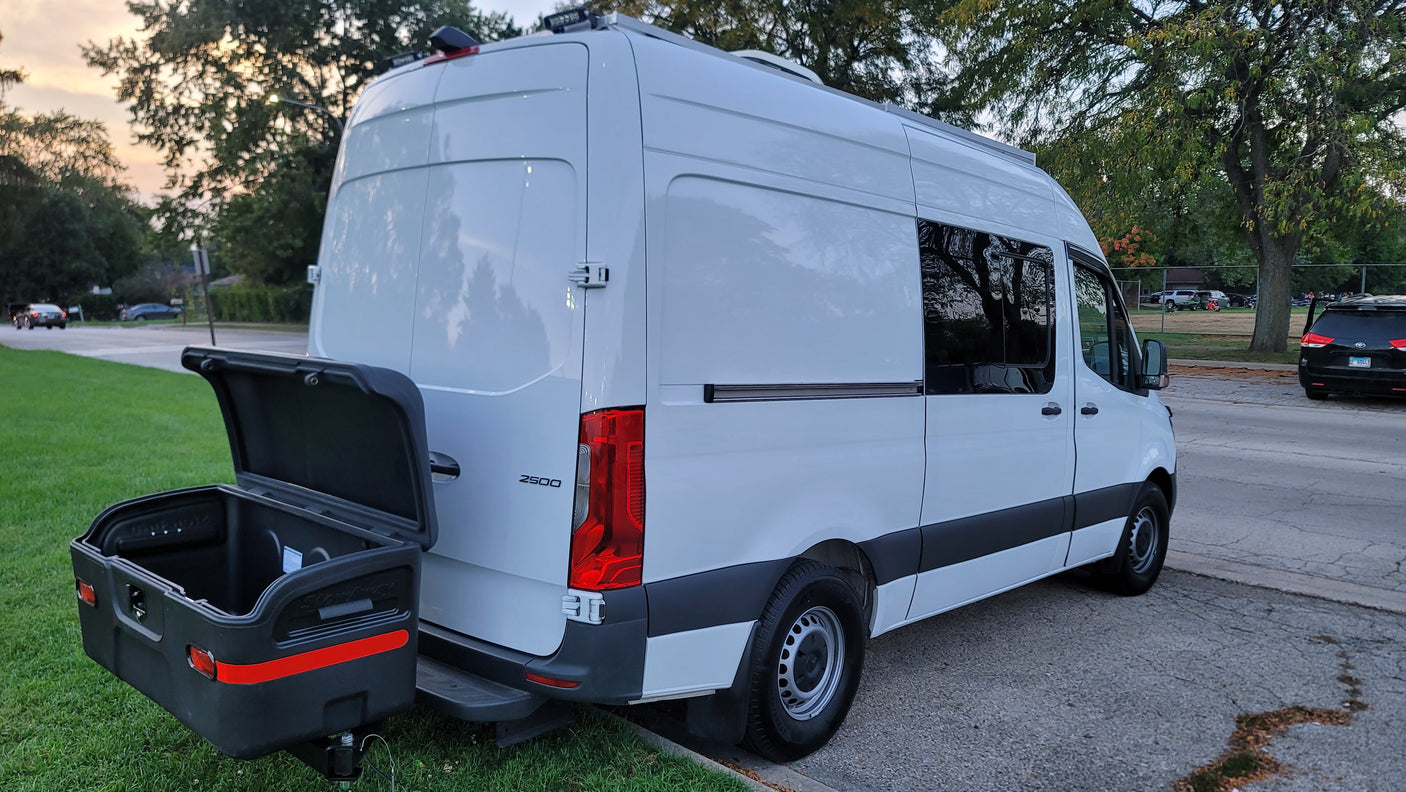 Rear view of a white Mercedes Sprinter 2500 camper van with an open cargo box, ready for rv rental.