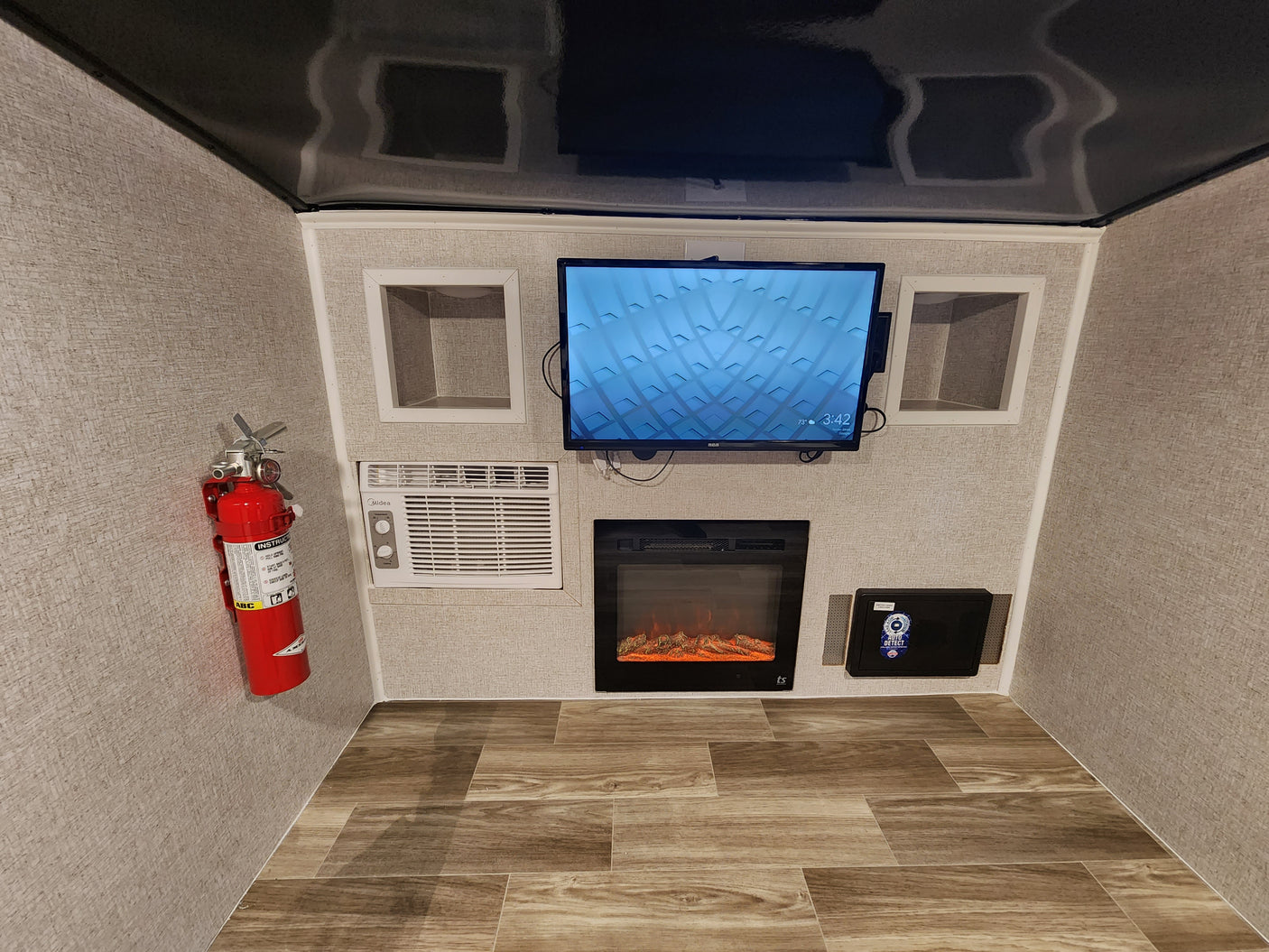 This rv rental's media nook offers a wall-mounted TV, electric fireplace, AC, and secure safe, with a fire extinguisher for safety.