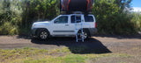 White Nissan Xterra with rooftop tent & ladder for your next **RV rental** adventure. Perfect for overland camping on dirt roads.