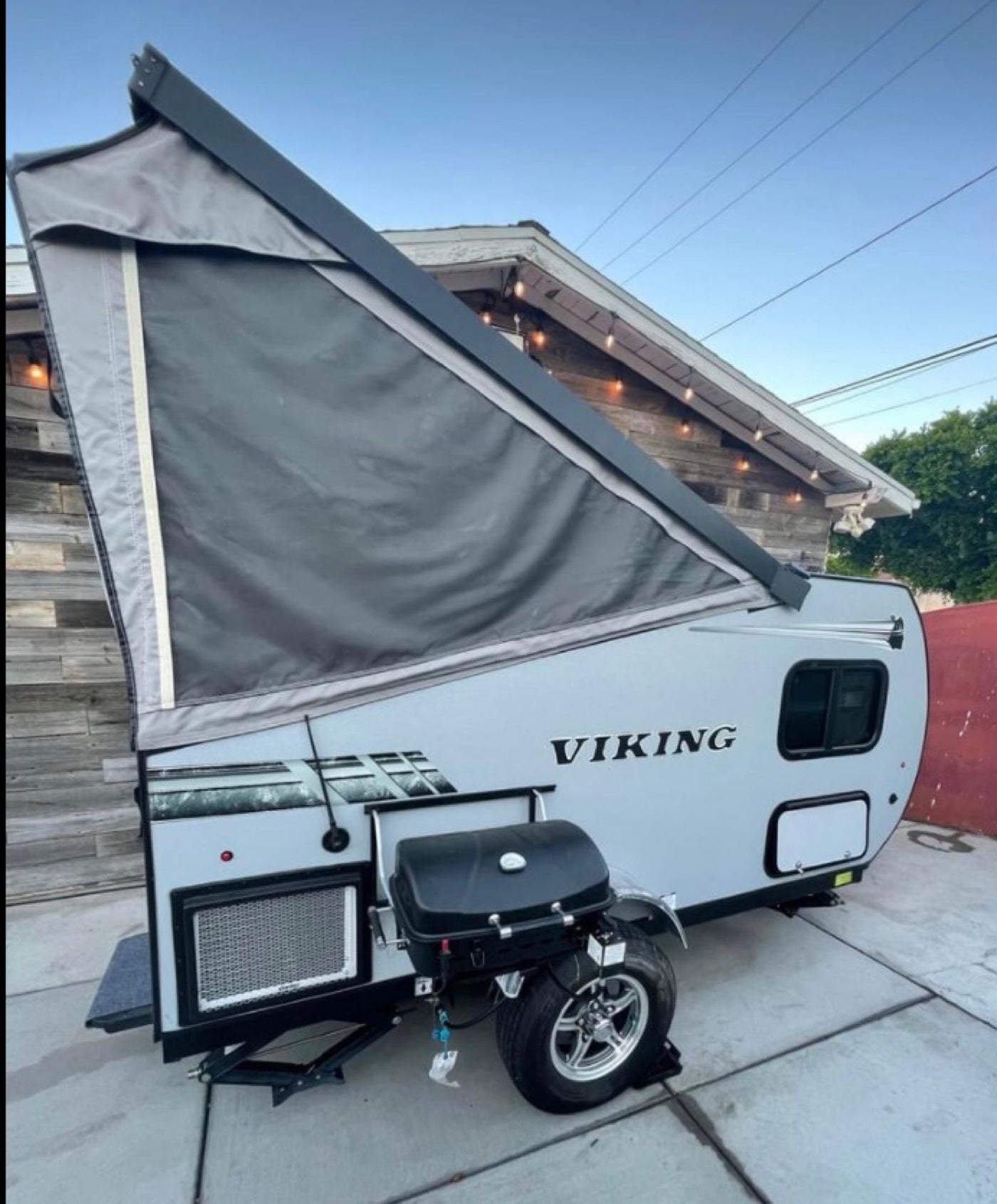  parked against a wooden wall with festive lights.|This A-frame Viking RV rental — photo 2