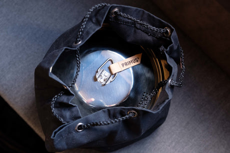 A Primus camping pot in a black drawstring bag, essential cookware for an RV rental trip.