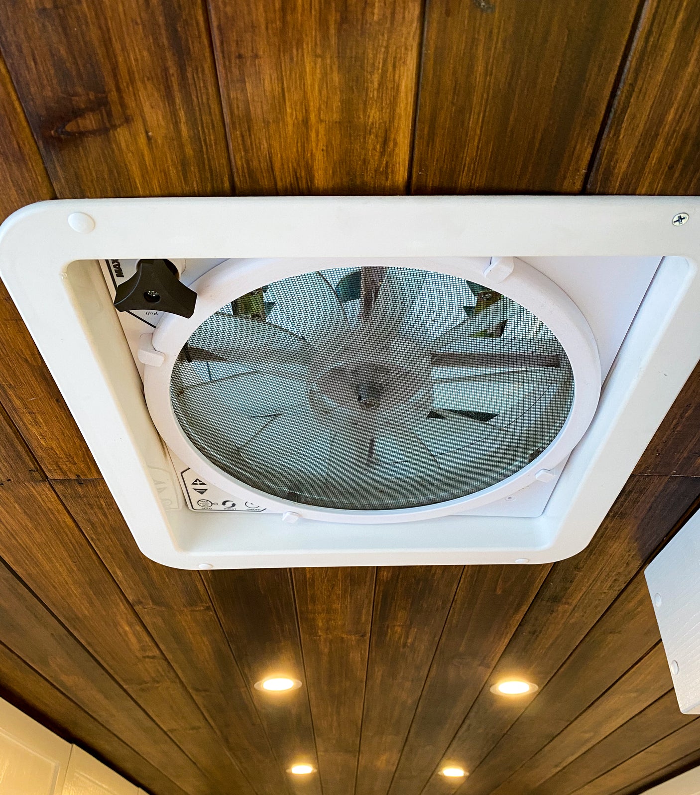 White ceiling fan with mesh screen, an essential rv rental feature, set in warm wood paneling with recessed lighting.