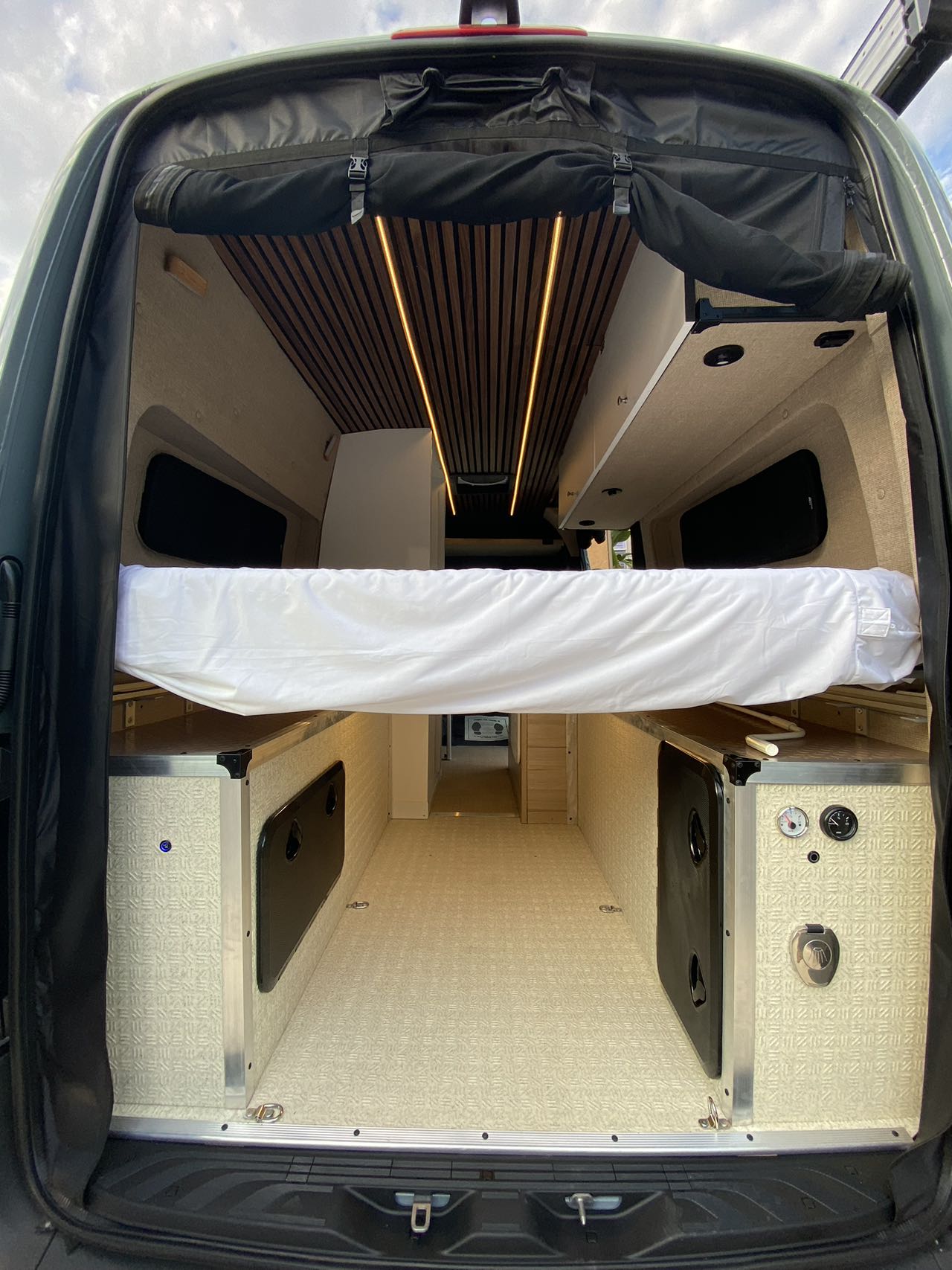  parked outdoors. Ready for your RV rental adventure.|Spacious RV rental interior: custom camper van with raised bed — photo 1