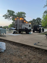 RV rental: A Viking pop-up camper with string lights is set up at a campsite next to a Jeep Wrangler at dusk.