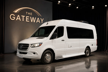 White Mercedes-Benz Sprinter camper van for RV rental, presented in a showroom featuring "THE GATEWAY" illuminated sign.