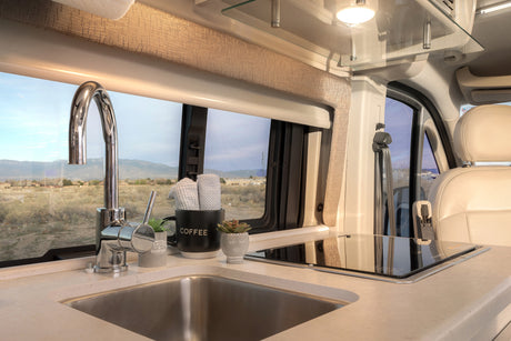 RV rental kitchen featuring a compact sink, induction cooktop, and scenic window view for comfortable mobile living.