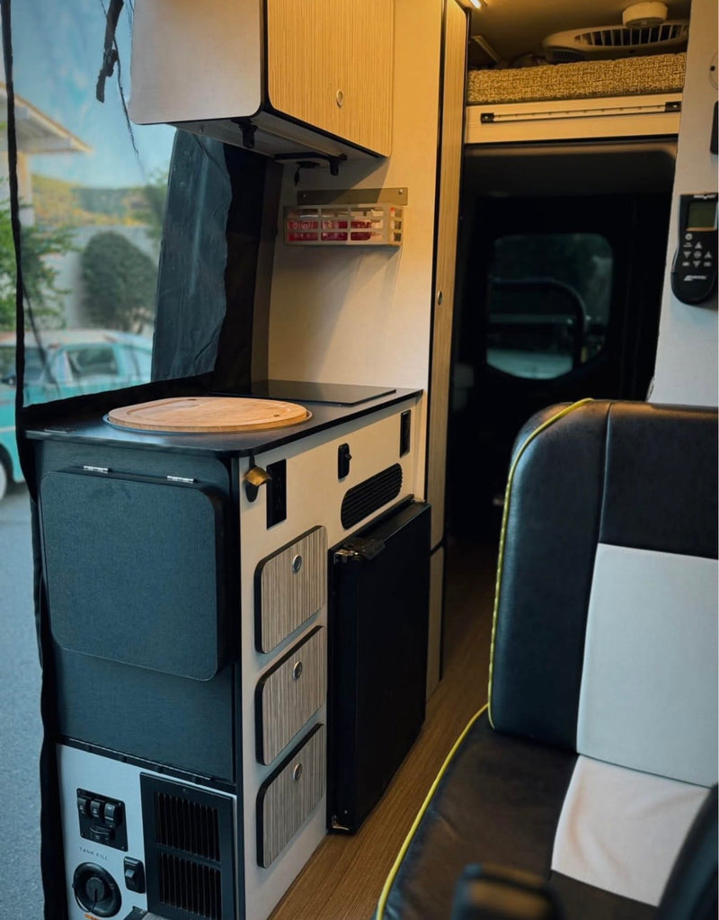 RV rental interior with a compact kitchen, cutting board, smart storage, and integrated controls for travel. — photo 12