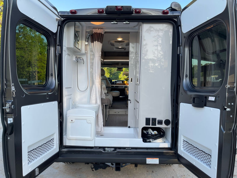 Explore this rv rental's rear: compact wet bath with shower, toilet, & utility storage. Perfect for mobile adventures! — photo 17