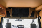 Spacious rv rental interior showing a large overhead screen, speakers, and front seats of a luxury van.