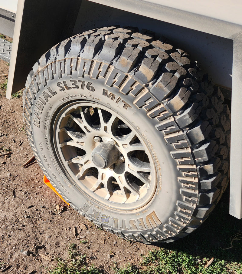 An RV rental's durable Westlake SL376 M/T tire and wheel, with an orange leveling block on dirt. — photo 17
