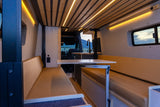 RV rental interior: spacious camper van living area with versatile Lagun table, lounge seating, & ambient lighting.