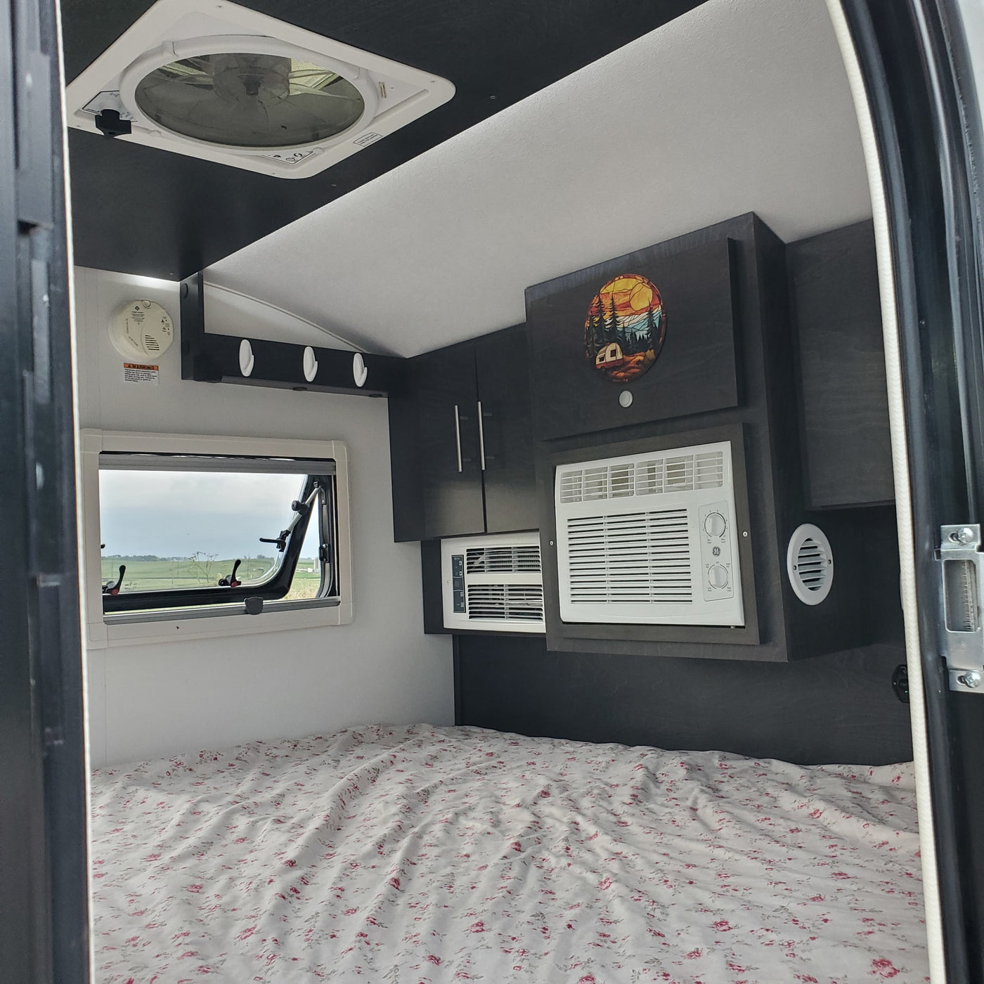 RV rental: Comfortable interior with bed, window, dual AC units, and overhead storage. — photo 15