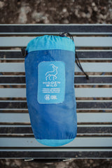 A blue Hidden Wild double travel hammock, neatly packed in its stuff sack on a slatted surface. Ideal for any RV rental trip.